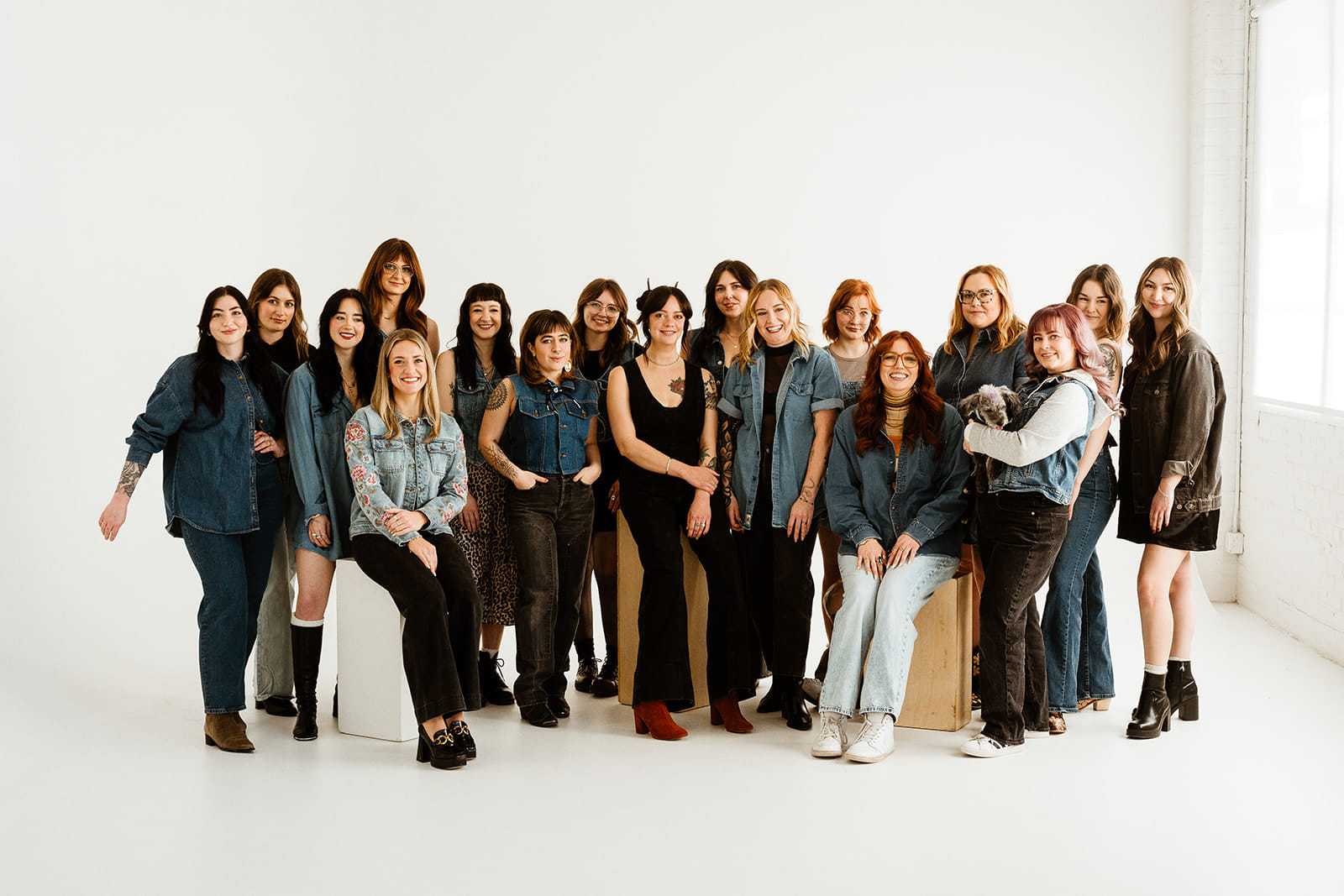Group of women posing against a white backdrop in casual attire, smiling and relaxed.